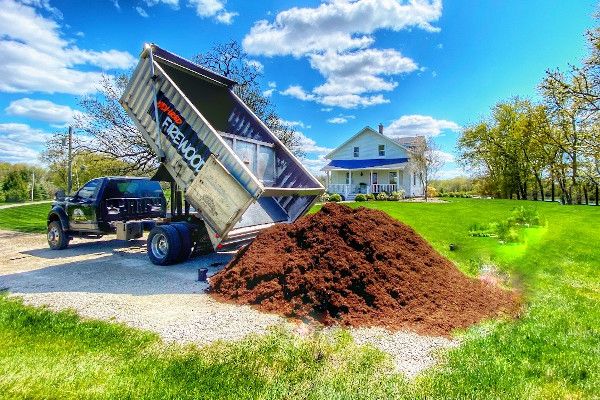 Image of a Lumberjacks truck dumping mulch in front of a house