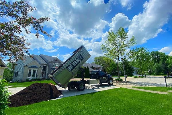 Image of a truck from Lumberjacks dropping off mulch on a driveway