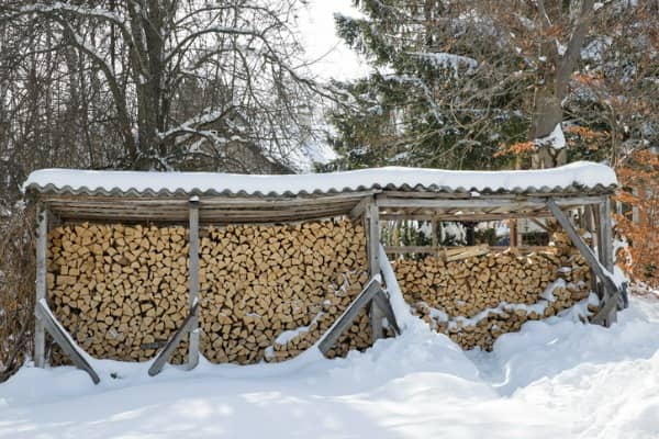 Stacked seasoned firewood sits in the snow