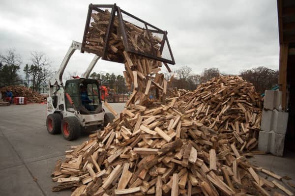 Lumberjacks add to a large pile of kiln-dried firewood