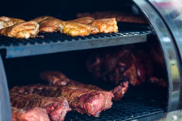A medley of red and white meat rests inside a heavy-duty smoker.