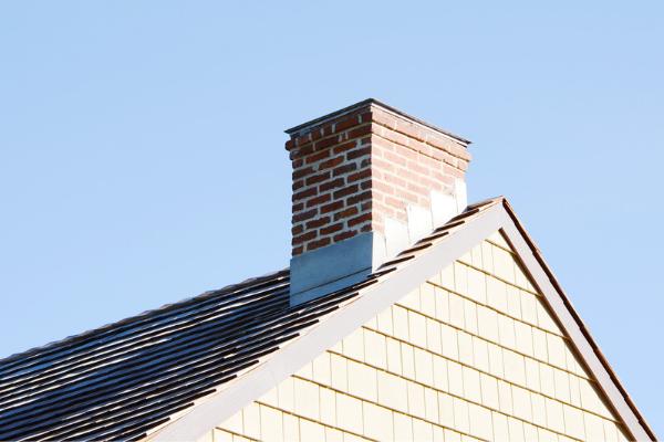 A chimney sticks out from a modest house.