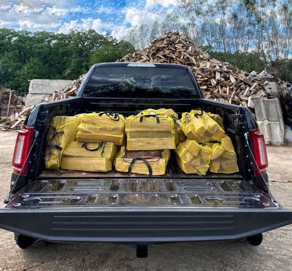 Image of bags of kiln-dried firewood in the back of a pickup truck.