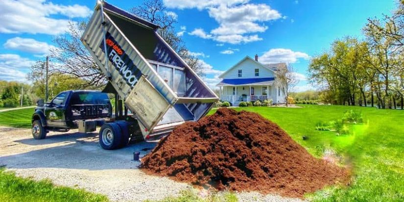 Image of a truck from Lumberjacks delivering premium mulch to a home.