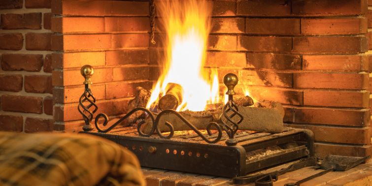 A warm, cozy fire is burning inside a home fireplace.