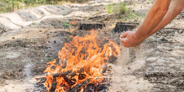 Person putting out a camp fire